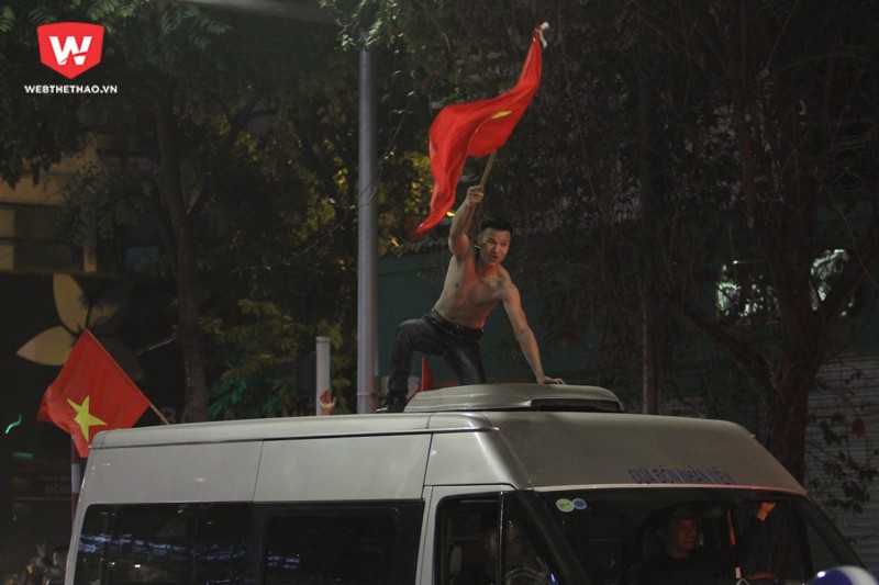 C&oacute; những thanh ni&ecirc;n ưa mạo hiểm, đứng hẳn l&ecirc;n n&oacute;c xe &ocirc; t&ocirc; để vẫy cờ ăn mừng. H&igrave;nh ảnh: Trung Thu.